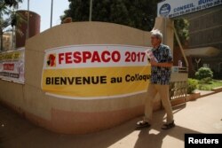 The Tunisian filmmaker Mohamed Challouf walks as he passes a banner during the Panafrican Film and Television Festival (FESPACO) in Ouagadougou, Burkina Faso, March 3, 2017.