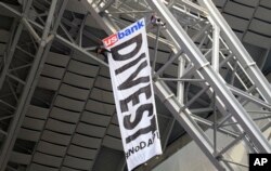 FILE - Protesters against the Dakota Access Pipeline rappel from the catwalk after placing a banner in U.S. Bank Stadium during an NFL football game between the Minnesota Vikings and Chicago Bears in Minneapolis, Jan. 1, 2017.