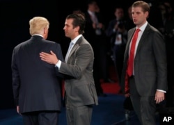FILE - Donald Trump talks to his sons Donald Trump Jr. and Eric Trump after the second presidential debate, Oct. 9, 2016.