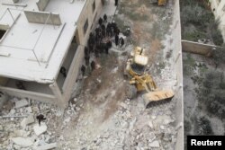 FILE - Civil defense workers remove dead bodies from under debris after an airstrike on Kafr Hamra village in the northern Aleppo countryside of Syria, Feb. 27, 2016.