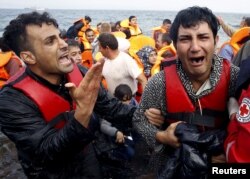 A Greek Red Cross volunteer comforts a crying Syrian refugee moments after disembarking from a flooded raft at a beach on the Greek island of Lesbos after crossing a part of the Aegean Sea from the Turkish coast by an overcrowded raft, Oct. 20, 2015.