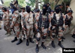Paramilitary soldiers stand guard, as they present men (unseen), who were detained during Wednesday's raid on the Muttahida Qaumi Movement political party headquarters, before an anti-terrorism court in Karachi, March 13, 2015.