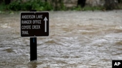 FILE - A sign is submerged in the water from Coyote Creek, Feb. 21, 2017, in Morgan Hill, Calif. Rains have saturated once-drought stricken California but have created chaos for residents hit hard by the storms.