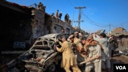 Warga setempat mengelilingi mobil yang hancur akibat ledakan bom, Rabu (2/2) di Peshawar.