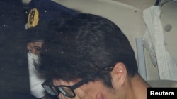 Takahiro Shiraishi covers his face inside a police car in Tokyo, in this photo taken by Kyodo November 2017 and released by Kyodo, Dec. 15, 2020.