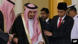 Indonesian President Joko Widodo (R) assists Saudi King Salman (C) as they walk during their meeting at the presidential palace in Bogor, West Java, Indonesia, March 1, 2017.
