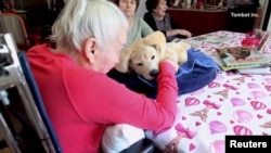 ภาพผู้สูงอายุที่กำลังเล่นกับหุ่นยนต์สุนัข "เจนนี"