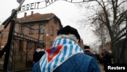 Survivors and guests walk past the "Arbeit Macht Frei" ("Work Sets You Free") gate at the former Nazi German concentration and extermination camp Auschwitz, during the ceremonies marking the 73rd anniversary of the liberation of the camp and International Holocaust Victims Remembrance Day, in Oswiecim, Poland, Jan. 27, 2018.