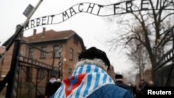 Para penyintas dan tamu berjalan melewati gerbang "Arbeit Macht Frei" di bekas konsentrasi Nazi Jerman dan kamp pemusnahan Auschwitz, dalam upacara peringatan ulang tahun ke-73 pembebasan kamp tersebut dan Hari Peringatan Korban Holocaust Internasional, di Oswiecim, Polandia, 27 Januari 2018. (Foto: dok).