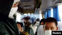 រូប​ឯកសារ៖ មន្ត្រី​សុខាភិបាល​ចិន​ពិនិត្យ​សីតុណ្ហភាព​នៃ​អ្នក​ដំណើរ​ម្នាក់​នៅ​ក្នុង​រថយន្ត​ក្រុង​ទៅ​កាន់​ទី​ក្រុង​វូហាន ធានី​​​ខេត្ត​ហ៊ុយបេ​ (Hubei) ប្រទេស​ចិន កាល​ពី​ឆ្នាំ​២០០៣ ក្នុង​អំឡុង​មាន​ការ​ផ្ទុះ​មេរោគ SARS។