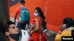 A man reacts as a healthcare worker collects a swab sample, amidst the spread of the coronavirus disease (COVID-19), at a railway station, in New Delhi, India, Apr. 7, 2021.