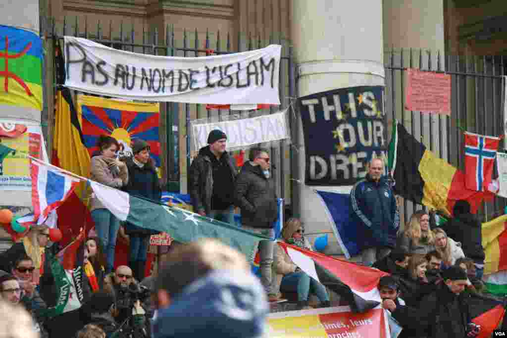 Over the course of the week, the steps of Brussel&rsquo;s stock exchange building have been decorated with flags from all over the world and messages of solidarity with the victims, including this banner that says &ldquo;Not in the name of Islam&rdquo; in French. (H.Murdock/VOA)