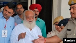 FILE - Police escort spiritual leader Asaram Bapu, center, outside an airport after his arrest in Jodhpur, in India's desert state of Rajasthan, Sept. 1, 2013.