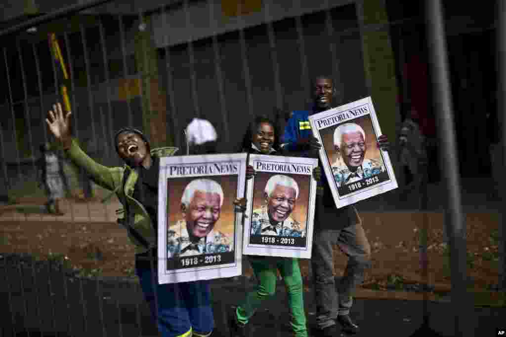 South African mourners hold posters of former president Nelson Mandela, while chanting slogans as the convoy transporting his remains passes by in Pretoria, Dec. 11, 2013.