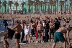 FILE - Police officers asks people to not sit while patrolling at the beach in Barcelona, Spain, May 20, 2020.
