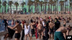 Police officers ask people to not sit while patrolling at the beach in Barcelona, Spain, May 20, 2020 after they were permitted to walk on its beaches for the first time since the start of the coronavirus lockdown over two months ago.