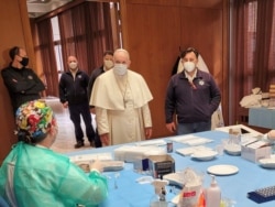 Pope Francis speaks to medical staff on Good Friday at a vaccination site at Paul VI Hall where the poor and homeless are being inoculated, at the Vatican, April 2, 2021. (Vatican Media/Handout via Reuters)