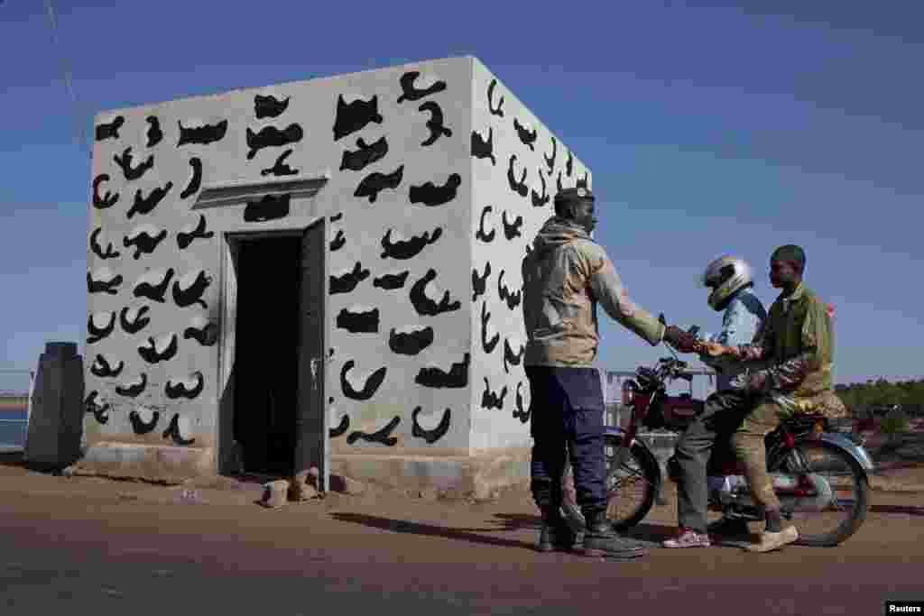 A Malian soldier checks the identity of people crossing a strategic bridge over a dam on the Niger River secured by French forces in Markala, Mali, January 18, 2013.
