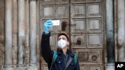 A man takes a selfie in front of the closed Church of the Holy Sepulchre, built in the location where Christians believe Jesus Christ was buried, in Jerusalem, March 25, 2020, as Israel tightens measures to fight the spread of the coronavirus.
