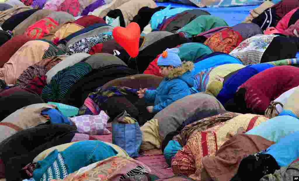 Seorang anak perempuan muslim Kashmir bermain dengan balon, sementara para perempuan Kashmir melakukan shalat pada peringatan Maulid Nabi Muhammad di Srinagar, Kashmir-India.
