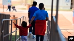 FILE - An Aug. 9, 2018, photo, provided by U.S. Immigration and Customs Enforcement, shows a woman and child walking at a Family Residential Center in Dilley, Texas. A mother and daughter deported to El Salvador were returned to a facility in Dilley late Thursday on orders of a U.S. judge. 