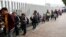 FILE - People line up to cross into the United States to begin the process of applying for asylum near the San Ysidro port of entry in Tijuana, Mexico, July 26, 2018. 