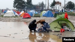 Migrants try to prepare a meal during a rainfall at a makeshift camp on the Greek-Macedonian border, near the village of Idomeni, Greece, March 9, 2016.