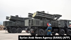 FILE - Russian soldier in ceremonial uniform stand by Pantsir-S SA-22 surface-to-air missile systems during the Victory Day military parade, at the Russian military Hmeimim base in south-east of the Syrian city of Latakia. 