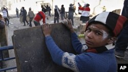 An Egyptian boy takes cover while others throw stones during clashes with the security forces near the interior Ministry in downtown Cairo, Egypt, February 3, 2012.
