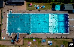 People spend time in a public pool in Wehrheim near Frankfurt, Germany, on a hot Saturday, July 8, 2023. (AP Photo/Michael Probst)