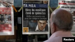 A man reads the front pages of various newspaper hanging at a kiosk in Athens, June 29, 2015. 