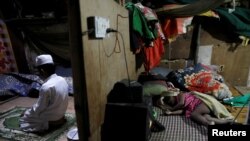 FILE - Rohingya refugee Shahid Hussain, 10, offers prayers after Iftar (breaking fast) time as his sister Sania, 2, sleeps in the next room at their house in a camp.