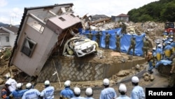 Rescue workers look for missing people in a house damaged by heavy rain in Kumano town, Hiroshima Prefecture, Japan, July 9, 2018. (Kyodo/via Reuters)