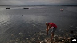 FILE - A man washes himself in the polluted waters of Guanabara Bay in Rio de Janeiro, Brazil, July 30, 2016. 