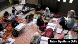 គ្រូបង្រៀន​ពាក់​របាំងការពារ​មុខ​ ពេលកំពុង​បង្រៀន​កូនសិស្ស​ដើម្បី​បង្ការ​កុំ​ឲ្យ​ឆ្លង​ជំងឺ​កូវីដ១៩ នៅ​ក្រុង Tangerang ប្រទេស​ឥណ្ឌូនេស៊ី ថ្ងៃ​ទី ១០ ខែសីហា ឆ្នាំ​២០២០។ 