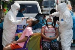FILE - Health workers conduct a COVID-19 swab test on residents at a village in Quezon City, Philippines, May 31, 2021.