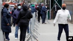 People stand in line as they wait to get tested for COVID-19 at a just-opened testing center in the Harlem section of New York, Monday, April 20, 2020. Hundreds of thousands of New Yorkers would need to be tested for the coronavirus daily before…