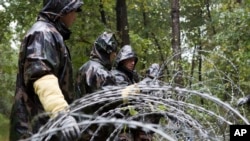 FILE - Hungarian soldiers put up spools of razor wire on Slovenian border in Zitkovci, Sept. 25, 2015. Hungary installed spools of razor wire near a border crossing with Slovenia, which like Hungary is part of the EU's Schengen zone of passport-free travel.