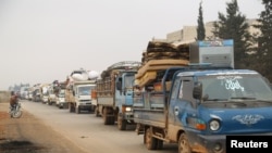 FILE - Trucks carry belongings of people fleeing from Maaret al-Numan, in northern Idlib, Syria, Dec. 24, 2019. 