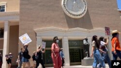 Black Lives Matter demonstrators chant the name of Breonna Taylor, who was killed by police officers during raid of her home in Louisville, Ky., outside the state capitol building on June 20, 2020, in Santa Fe, New Mexico. 