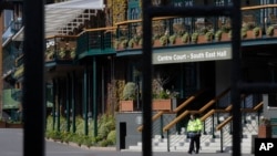 An officer guards the famed tennis championships center in Wimbledon as the All England Club announced the cancellation of the 2020 tournament in response to the coronavirus on Wednesday, April 1, 2020. (AP Photo/Kirsty Wigglesworth)