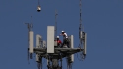Workers install 5G telecommunications equipment on a T-Mobile tower in Seabrook, Texas, May 6, 2020.