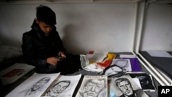 FILE - Farhad Nouri sits on a bed by a portrait of Serbian tennis player Novak Djokovic, left, Spanish surrealist painter Salvador Dali, second from left, and German Chancellor Angela Merkel, third from left, in his room in the "Krnjaca" collective center near Belgrade, Serbia, March 13, 2017.