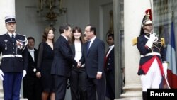 Mantan Presiden Nicolas Sarkozy (dua dari kiri) berjabat tangan dengan presiden baru Francois Hollande (kanan) di akhir upacara pelantikan presiden Perancis di Istana Elysee di Paris (15/5). Nampak mantan ibu negara Carla-Bruni Sarkozy (dua dari kanan) da
