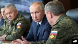 FILE - Russian President Vladimir Putin, center, and Russian Defense Minister Sergei Shoigu, left, attend the main stage of the Kavkaz-2020 strategic command-and-staff exercises at the Kapustin Yar training ground, Russia, Sept. 25, 2020.