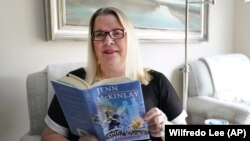 Kelly Vaiman is a great fan of cozy mysteries. They helped her deal with sorrow during the pandemic. Here she reads a cozy in her living room in Boynton Beach, Florida, February 19, 2021. (AP Photo/Wilfredo Lee)
