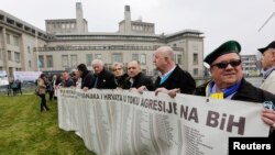 ជន​រង​គ្រោះ​បូស្ន៊ី និង​សមាជិក​គ្រួសារ​របស់​ពួកគេ​ប្រមូល​ផ្តុំ​​នៅ​ខាង​ក្រោ​តុលាការ​ព្រហ្មទណ្ឌ​សម្រាប់​អតីត​ប្រទេស​យូហ្គោស្លាវី មុន​ពេល​ប្រកាស​សាលក្រម​នៅ​ក្នុង​សវនការ​ប្រល័យ​ពូជសាសន៍​មួយ​លើ​លោក Radovan Karadzic ក្នុង​ក្រុង​ឡាអេ ប្រទេស​ហូឡង់ កាលពី​ថ្ងៃទី២៤ ខែមីនា ឆ្នាំ២០១៦។