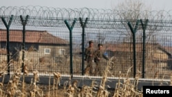 FILE - North Korean soldiers patrol behind a border fence near the North Korean town of Sinuiju, March 31, 2017. 