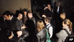 In this Thursday, December 29, 2011 file photo, workers from one of the US non-governmental organizations, the National Democratic Institute, wait as Egyptian officials raid their office in Cairo.