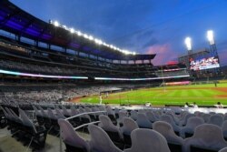 FILE - Cardboard cutouts of fans in the otherwise empty seats at Truist Park face the field during the sixth inning of a game between Atlanta and visiting Tampa Bay, July 30, 2020.